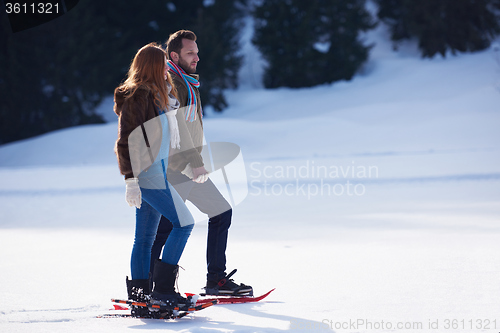 Image of couple having fun and walking in snow shoes