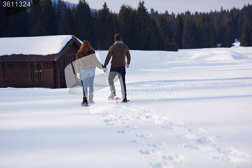 Image of couple having fun and walking in snow shoes