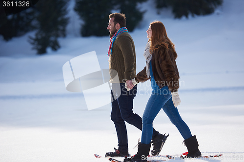 Image of couple having fun and walking in snow shoes
