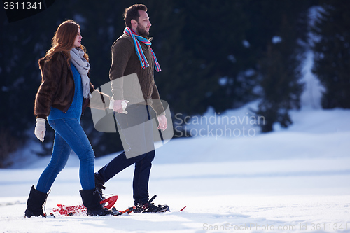 Image of couple having fun and walking in snow shoes