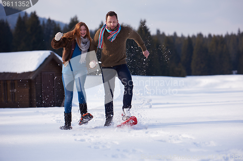 Image of couple having fun and walking in snow shoes