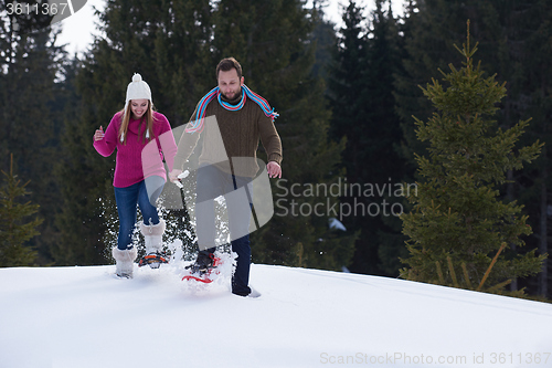 Image of couple having fun and walking in snow shoes