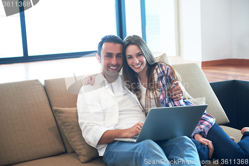 Image of relaxed young couple working on laptop computer at home