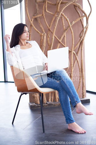 Image of relaxed young woman at home working on laptop computer