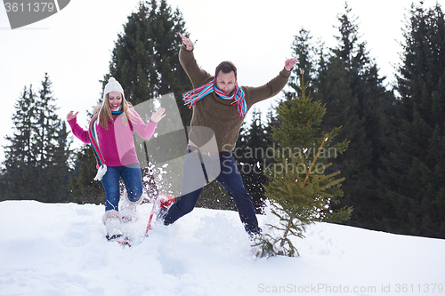 Image of couple having fun and walking in snow shoes