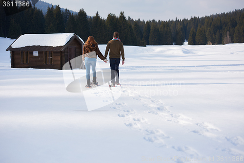 Image of couple having fun and walking in snow shoes