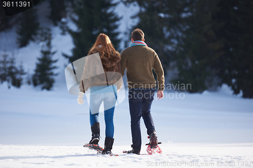 Image of couple having fun and walking in snow shoes