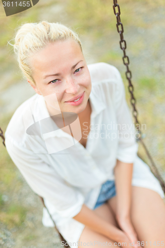 Image of Young blonde woman sitting on the swing