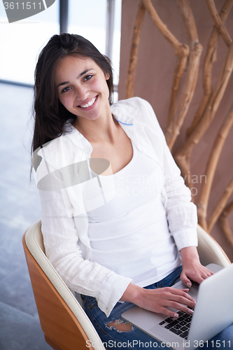 Image of relaxed young woman at home working on laptop computer