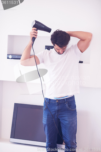 Image of handsome man using  hairdryer