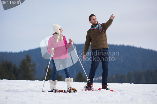 Image of couple having fun and walking in snow shoes