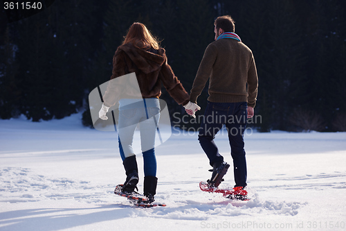 Image of couple having fun and walking in snow shoes