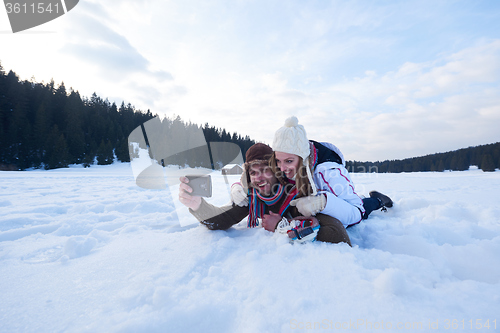 Image of romantic couple have fun in fresh snow and taking selfie