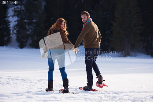 Image of couple having fun and walking in snow shoes