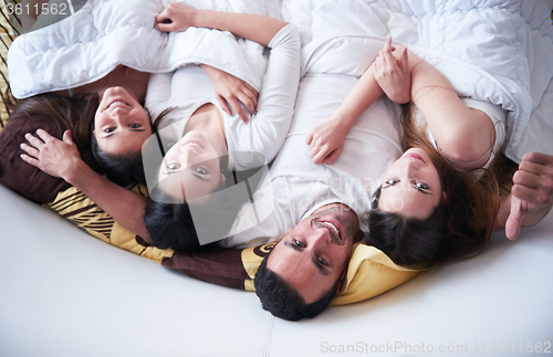 Image of handsome man in bed with three beautiful woman