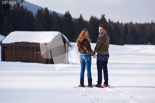 Image of couple having fun and walking in snow shoes