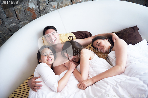 Image of handsome man in bed with three beautiful woman