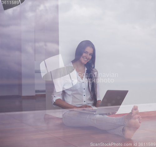 Image of relaxed young woman at home working on laptop computer