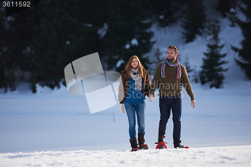 Image of couple having fun and walking in snow shoes