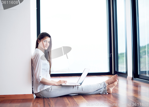 Image of relaxed young woman at home working on laptop computer