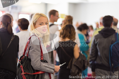 Image of Young blond caucsian woman waiting in line.