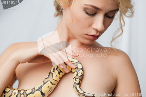 Image of Beautiful girl  holding a python, which wraps around her body