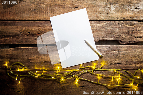 Image of The blank sheet of paper on the wooden table with a pen 