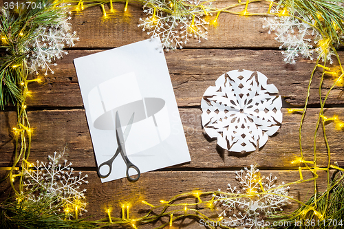 Image of The blank sheet of paper on the wooden table with a scissors 