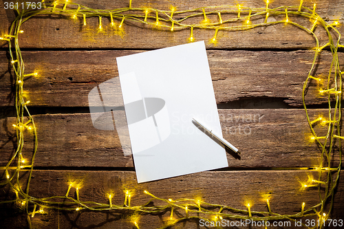 Image of The blank sheet of paper on the wooden table with a pen 