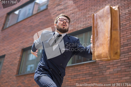 Image of young businessman running in a city street