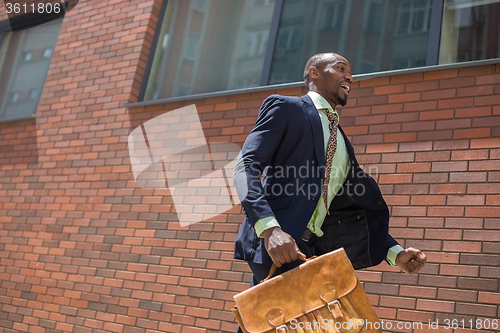 Image of african black young businessman running in a city street