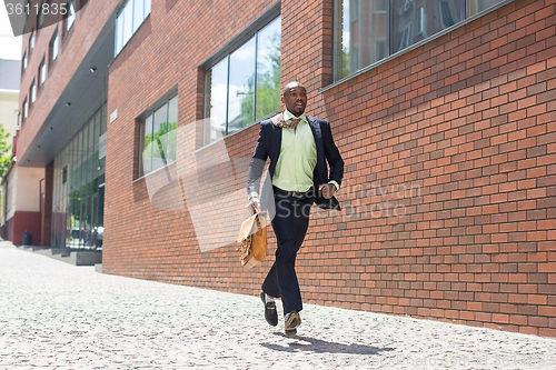 Image of african black young businessman running in a city street