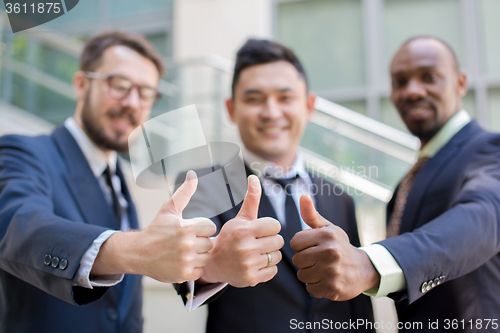 Image of Close-up of business team holding their thumbs up