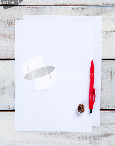 Image of The blank sheet of paper on the wooden table with a pen 