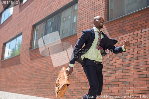 Image of african black young businessman running in a city street