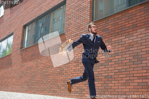 Image of young businessman running in a city street