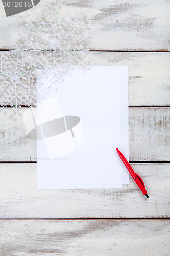Image of The blank sheet of paper on the wooden table with a pen 