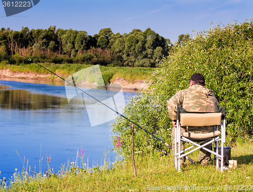 Image of Fisherman with a fishing rod on the river Bank.