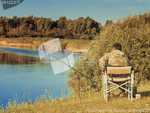 Image of Fisherman with a fishing rod on the river Bank.