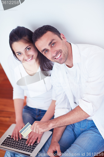 Image of relaxed young couple working on laptop computer at home