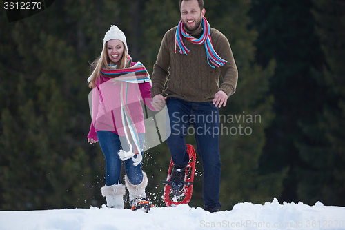 Image of couple having fun and walking in snow shoes