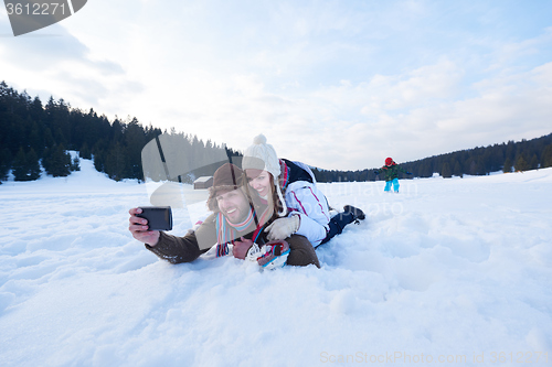 Image of romantic couple have fun in fresh snow and taking selfie