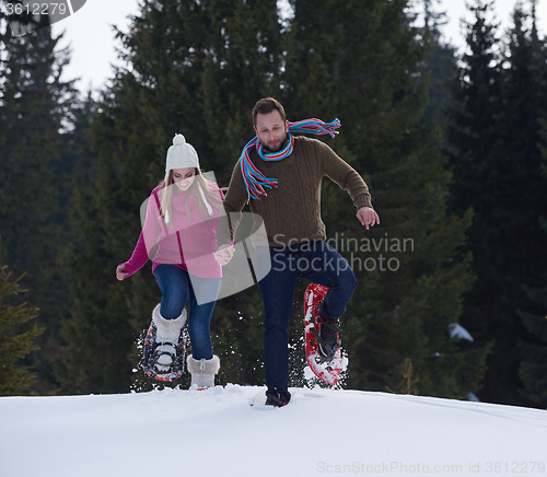 Image of couple having fun and walking in snow shoes