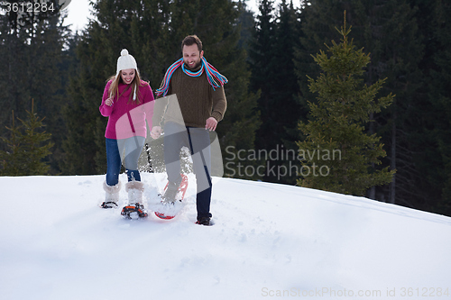 Image of couple having fun and walking in snow shoes