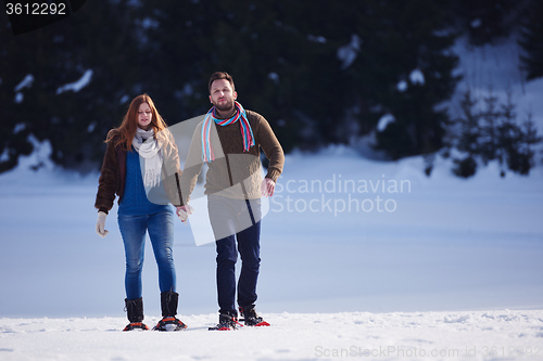 Image of couple having fun and walking in snow shoes