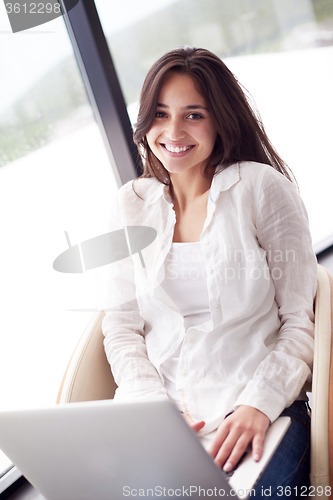 Image of relaxed young woman at home working on laptop computer