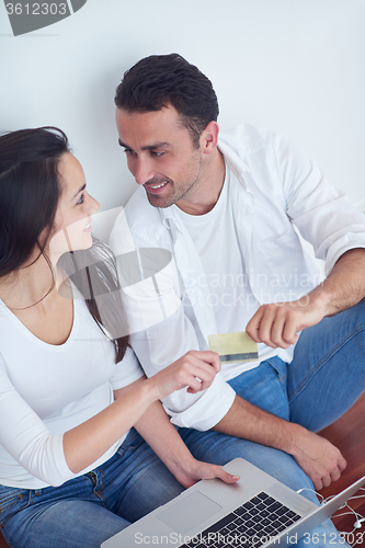 Image of relaxed young couple working on laptop computer at home