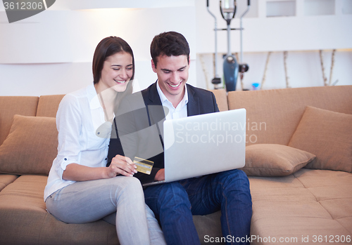 Image of relaxed young couple working on laptop computer at home