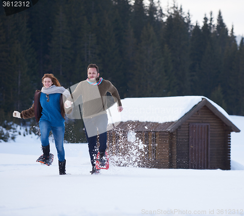 Image of couple having fun and walking in snow shoes