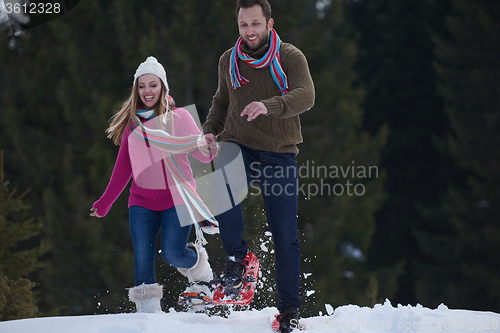 Image of couple having fun and walking in snow shoes